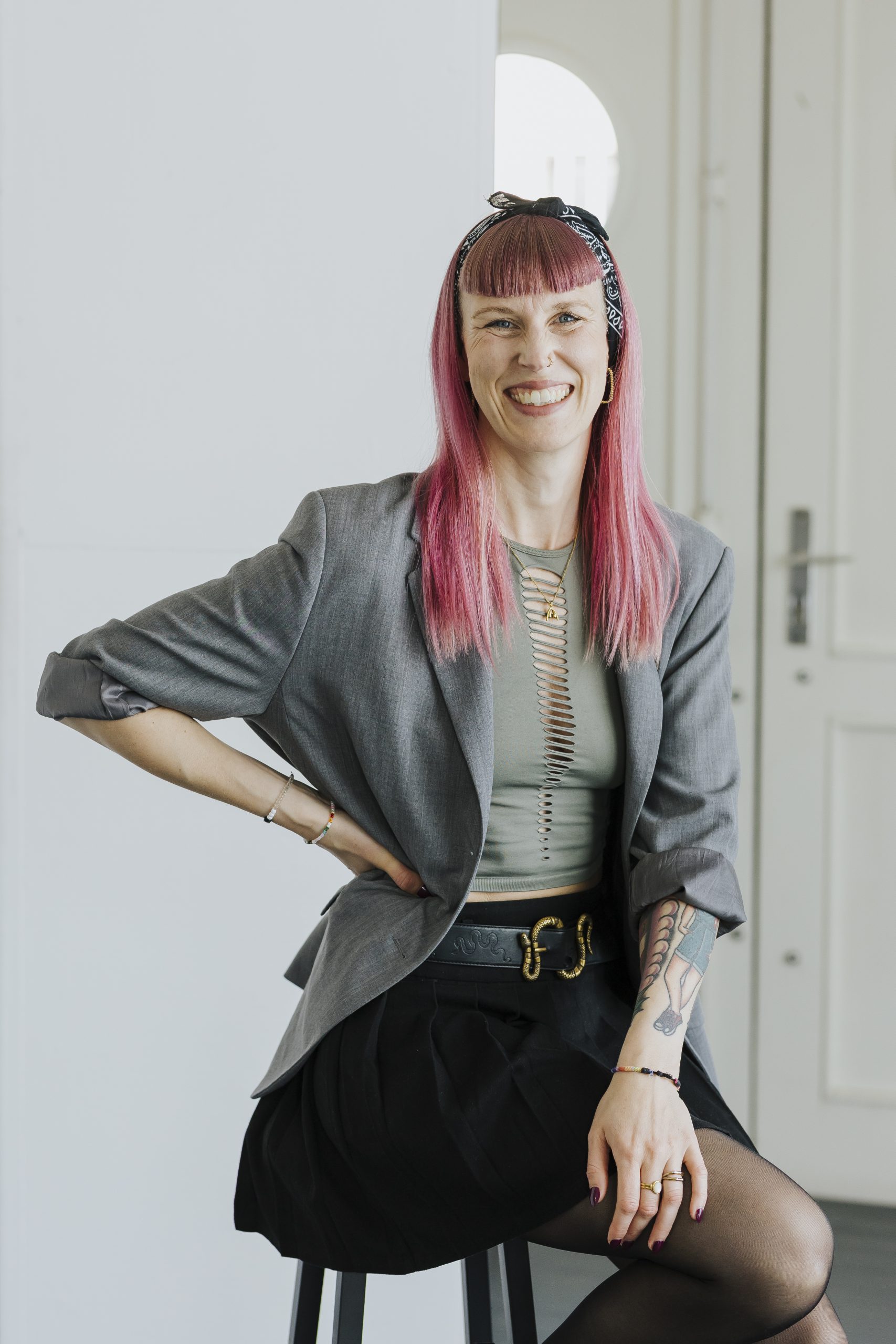 Sarah Blume, sitzend auf einem Hocker, lächelnd